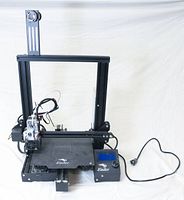 Front view of assembled printer showing frame, magnetic bed, extruder and control box with power cord