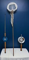 Full lot photo showing two fishing rods with reels and a fishing net on a blue background, displayed against a white surface.