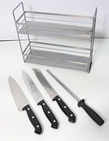 Photo of two Henkels knives, one additional chef knife with curved blade, knife sharpener rod with black handle, and grey metal kitchen rack.