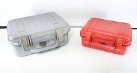 Photo showing full set of two hard plastic Pelican cases, a larger grey one and smaller red one side by side, both closed.