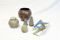 Photo of the entire six-piece pottery lot including the brown round pot, green dresser pot with lid, salt and pepper set, Humpty Dumpty salt shaker, and French bread holder.