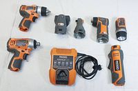 Nine Ridgid items on white background: two drill drivers, impact driver, charger, power handle and four heads.