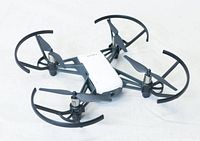 Tello Micro Drone with prop guards laid on white surface