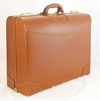 Front and side view of vintage tan leather suitcase with brass locks and two leather handles