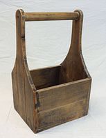 Front and side view of wooden open tool box showing general shape, handle, and finish.