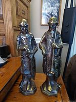 Front view of both antique bronze statues side by side, showing full height and posture.