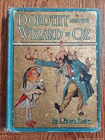 Front cover of antique 1908 book 'Dorothy and the Wizard in Oz' showing Dorothy and the Wizard illustration with visible wear and aging.