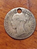 Obverse side of the 1876 Queen Victoria silver threepence coin showing left-facing young head portrait with drilled hole near the top edge, worn surface with spots and discoloration.