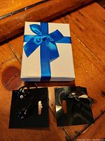Closed white and blue gift box with blue satin ribbon bow, set containing watch and orca jewelry items.