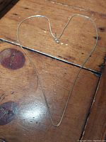 Full view of 10k gold chain necklace laid out on wooden surface showing overall length and broken clasp