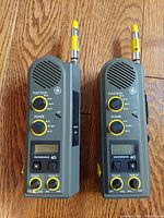 Front view of two GE 3-5985A Weatherband CB radios with yellow control knobs and antennas, showing missing volume button caps.