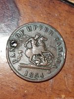Obverse side of 1854 Bank of Upper Canada bank token showing Saint George slaying dragon, year 1854.
