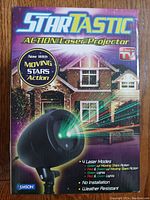 Box front of StarTastic Action Laser Projector showing laser light effect on house with moving stars action and listing features.