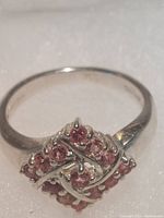 Close-up photo of sterling silver ring with pink tourmaline gemstone cluster on a white textured background showing front and side of ring.