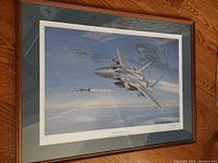 Framed print of military aircraft with grim reaper image in the sky, signed and numbered, showing wood frame and green mat