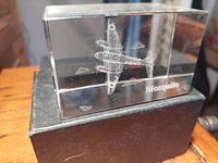Angle view of the clear crystal block with detailed 3D laser-etched Mosquito aircraft inside, resting on a black base, showing clarity and etching details.