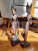 Front view of two vintage Southeast Asian hardwood carvings representing aristocratic figures, highlighting intricate carving and detailed headwear