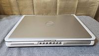 Closed Dell E1505 laptop showing silver top cover with Dell logo and white chassis sides with front controls.
