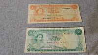Front view of 1968 Bahamas five-dollar and one-dollar paper bills showing Queen Elizabeth II portrait and denomination details.