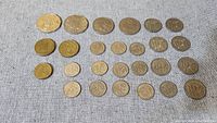 Top down view of all 26 coins laid out on fabric background showing different denominations and sizes