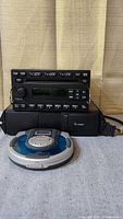 The lot photo showing the Ford radio/CD player, VW 6-disc CD changer, and portable single disc CD player placed on a surface with a neutral backdrop.