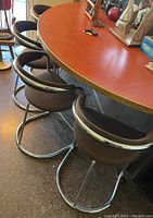 Three brown fabric and metal bar/counter stools lined up next to a counter with reddish laminate top