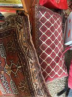 Two red patterned rugs with geometric designs, partially folded showing woven details