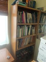 Wooden bookshelf with books on all shelves photographed from the side showing shelf dimensions and overall condition