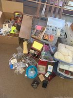 Wide view showing assortment of costume jewelry pieces, yarn, and jewelry making molds scattered on the floor with boxes and containers