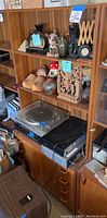 Photo showing upper hutch shelves holding various decorative items, lower part with a turntable and audio equipment, and drawers below.