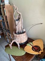 Photo showing the three sculptures and the two drums arranged on wooden surfaces, featuring the fountain with driftwood and basket, spiral sculpture with moss, and stingray sculpture with metal and wood elements.