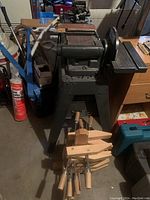 Overall view of Craftsman bench sander on metal stand with wooden clamps stacked at base
