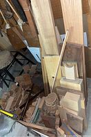 Vertical stack of planed hardwood boards and assorted turning blanks in front