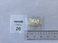 Photo showing the 1851 3 pence coin or token in a plastic sleeve next to a ruler for size reference.