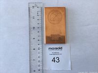 Photo of a .999 copper ingot bar 1/2 lb alongside a ruler for scale, showing clear stamped markings and smooth finish.
