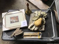 Lot on table showing all items: framed art, brass bell, ceramic fruit decor, and brass fly ashtray.