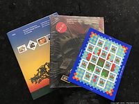 Photo of three Canada Post souvenirs: two stamp collection booklets from 1990 and 1992 and a sealed 1996 Canada Day souvenir sheet featuring floral stamps with colorful geometric borders.