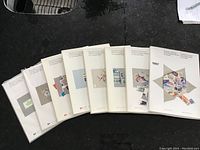 All eight souvenir stamp collection booklets from 1980 to 1987 displayed side by side, showing their white and beige spines and covers.