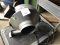 View of the fan showing the intake and the overall housing with air outlet, placed on a platform.