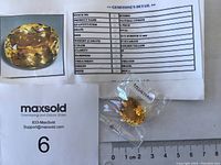 Photo of the yellow oval citrine gemstone on a ruler with a document showing its details including weight, size, color, clarity, hardness, treatment, and origin.
