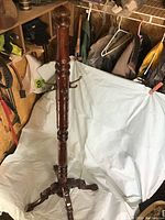 Full view of tall wooden coat rack standing upright showing carved details and hooks.