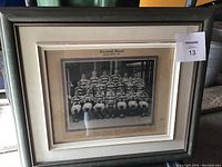 Full view of the framed football team photograph showing the group in striped jerseys and the frame's style.