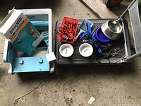 Overall shot showing the automatic cat litter box in light blue, multiple extra bins, box packaging, red and blue harnesses and leashes, two white bowls, stainless steel refrigerated bowl, and various pet accessories on cart.
