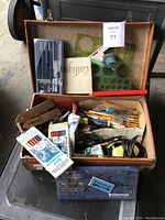 Top view of open suitcase filled with drafting tools, templates, colored pencils, and stationery items.