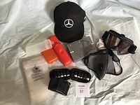 Photo showing Bolle goggles, Mercedes cap, cold weather mask, wrist guards, and small accessory items arranged on cloth.