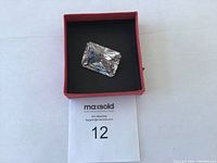 Top view of the large clear lab created diamond inside a red box on white background showing its rectangular cut and facets.