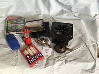 Photo showing survival set items: folding stove, burners, candle holder, candles, shelter tent package and blue container.