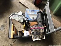 Overview of multiple items in the lot including saws, trowels, leather belt, and packaged latches