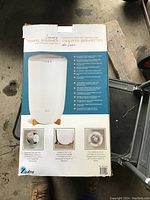 Photo of the towel warmer product box showing the towel warmer image with brand, features, and bamboo base accent details.