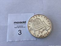 Coin with MaxSold support card showing lot marker